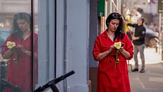 ARQUIVO (08.03.2025): Uma mulher segura uma flor enquanto olha para um telemóvel no Dia Internacional da Mulher, no centro de Bucareste.