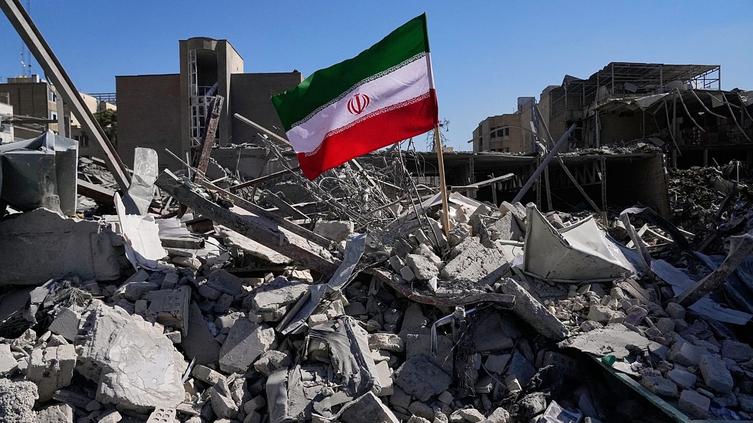 رچم ایران در میان ویرانه‌های یک ایستگاه پلیس که روز دوشنبه در جریان کارزار نظامی آمریکا و اسرائیل در تهران هدف حمله قرار گرفت