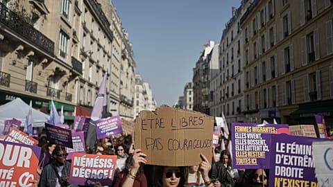 A woman holds a placard reading "Be free, not brave", center, as she takes part in a march to mark International Women's Day in Paris, Sunday, March 8, 2026.