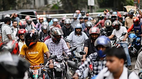 Motorists queue up as others wait behind a rope for their turn to get fuel at a pump, fearing a possible fuel shortage due to the Iran war, in Dhaka, Bangladesh