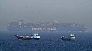 Two traditional dhows sail by a large container ship in the Strait of Hormuz, 19 May, 2023
