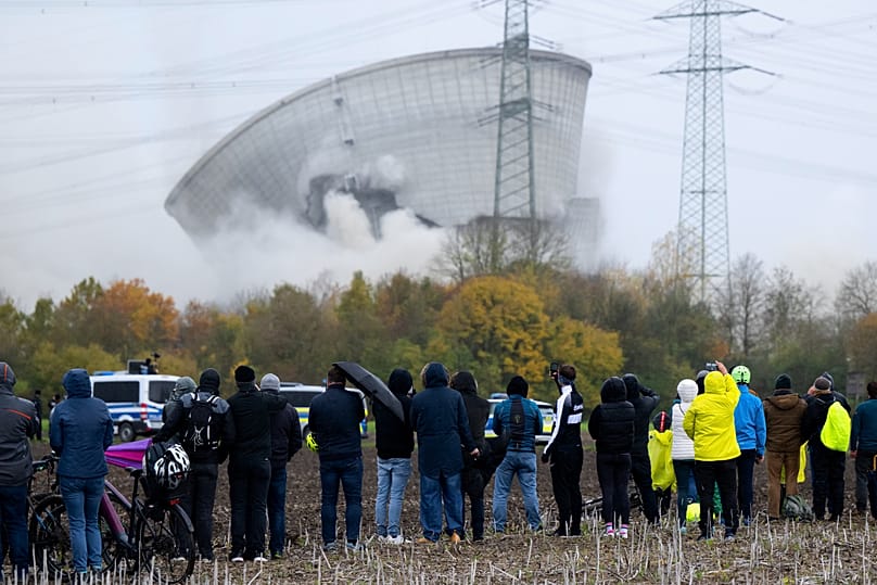 People watch as the second cooling tower of the decommissioned Gundremmingen nuclear power plant collapses after blasting, in Gundremmingen, Germany, Saturday, Oct. 25, 2025. 