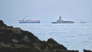 A UAE navy ship sails next to a cargo ship in the Strait of Hormuz as seen from Khor Fakkan, United Arab Emirates, Wednesday, March 11, 2026. 