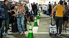 Fluggäste warten im Parkhaus vor dem Terminal in langen Schlangen auf die TSA-Sicherheitskontrolle.