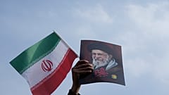 رجل يرفع علم إيران وملصقاً للمرشد الأعلى الراحل آية الله علي خامنئي خلال مهرجان دعم لابنه، آية الله مجتبى خامنئي، الذي خلف والده كمرشد أعلى جديد