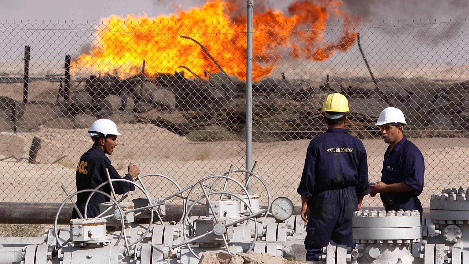عمال عراقيون في مصفاة رومَيْلة للنفط بالقرب من مدينة البصرة، على بعد 550 كيلومترًا جنوب شرق بغداد، العراق.
