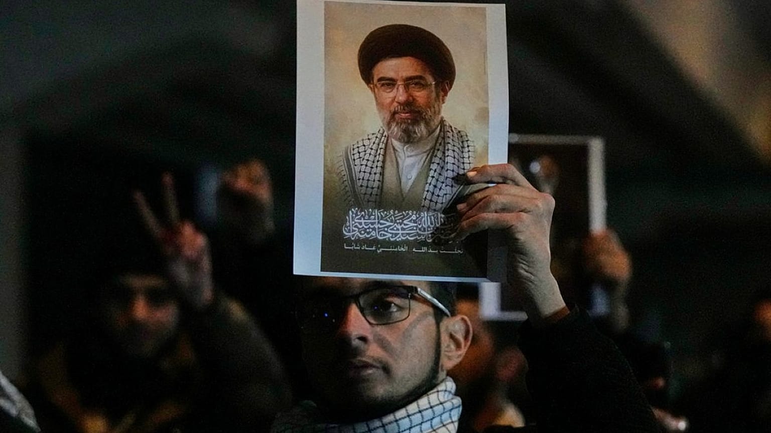 عراقيون يحملون صورة  للمرشد الأعلى الجديد لايران مجتبى خامنئي، على جسر يؤدي إلى المنطقة الخضراءبغداد، العراق، يوم الاثنين 9 مارس 2026.