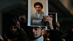 عراقيون يحملون صورة  للمرشد الأعلى الجديد لايران مجتبى خامنئي، على جسر يؤدي إلى المنطقة الخضراءبغداد، العراق، يوم الاثنين 9 مارس 2026.