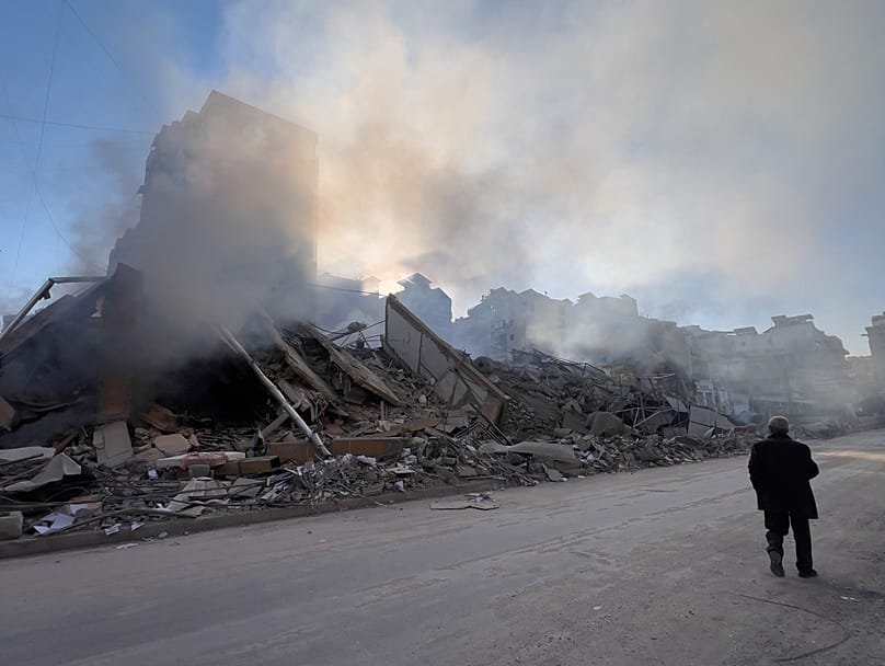A man passes in front of a destroyed building housing Al-Qard Al-Hassan, a non-bank financial institution run by Hezbollah, in Dahiyeh, Beirut, Tuesday, March 10, 2026