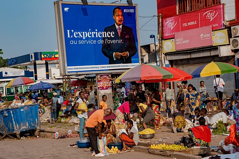 An election poster featuring President Denis Sassou N'Guesso stands over a market in central Brazzaville, Congo, Sunday March 7, 2021. 