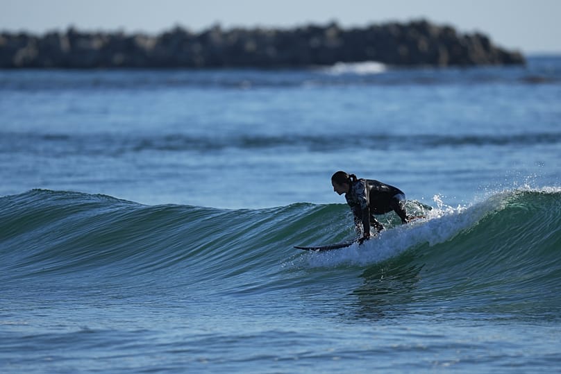 A surfer prepares to ride a wave at Toyoma beach in Iwaki, northeastern Japan, Tuesday, Feb. 10, 2026.