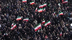 يحمل المشيعون الأعلام الإيرانية بينما يحضر حشد من الناس موكب جنازة كبار المسؤولين العسكريين الإيرانيين والمدنيين الذين قتلوا خلال الحملة الأمريكية الإسرائيلية في طهران، إيران،