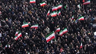 يحمل المشيعون الأعلام الإيرانية بينما يحضر حشد من الناس موكب جنازة كبار المسؤولين العسكريين الإيرانيين والمدنيين الذين قتلوا خلال الحملة الأمريكية الإسرائيلية في طهران، إيران،