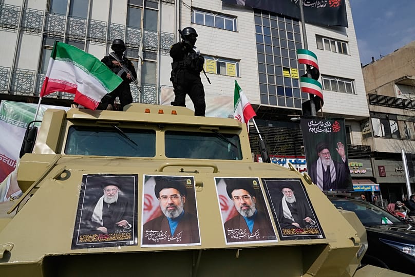 FILE: Policemen stand on top of their car with pictures of late Iranian Ayatollah Ali Khamenei and his son Ayatollah Mojtaba Khamenei, during a rally in Tehran, 9 March 2026