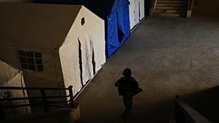 A displaced child plays past tents set up inside the Camille Chamoun Sports City Stadium, which has been turned into a shelter for displaced people in Beirut, 10 March 2026