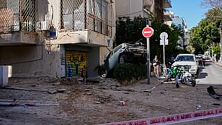 امرأة تمر بجوار منطقة مغلقة تضررت خلال غارة جوية في تل أبيب، إسرائيل، الأحد 8 مارس 2026. (صورة AP/أوهاد زويجنبرج)