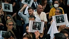 ARCHIVO - Varias personas portan imágenes del fallecido fiscal antidrogas Marcelo Pecci durante una protesta tras su asesinato en Asunción, Paraguay, el 13 de mayo de 2022.