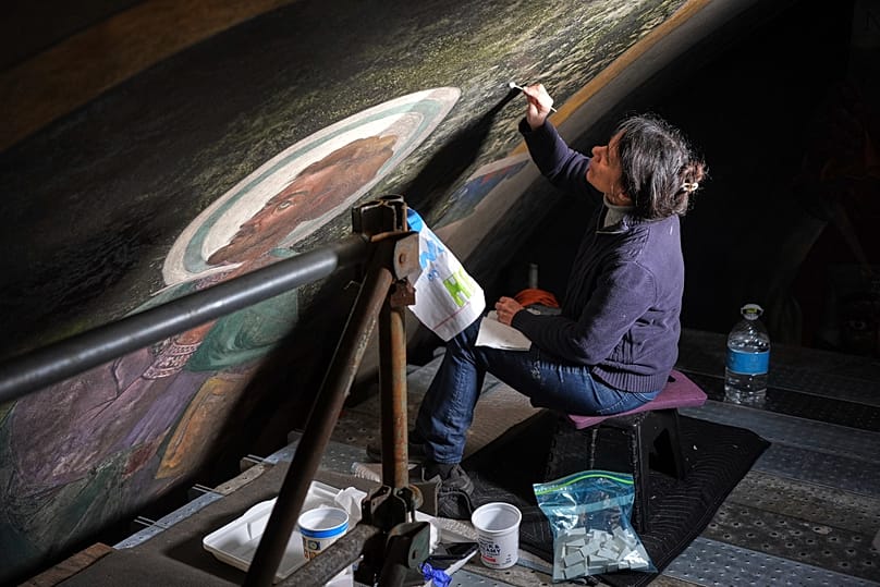 فنية حفظ الأعمال الفنية سيليست باريندو تعمل على جزء من الجداريات داخل كنيسة القديس نيكولاس الكرواتية الكاثوليكية في ميلفيل، الولايات المتحدة، 2025.