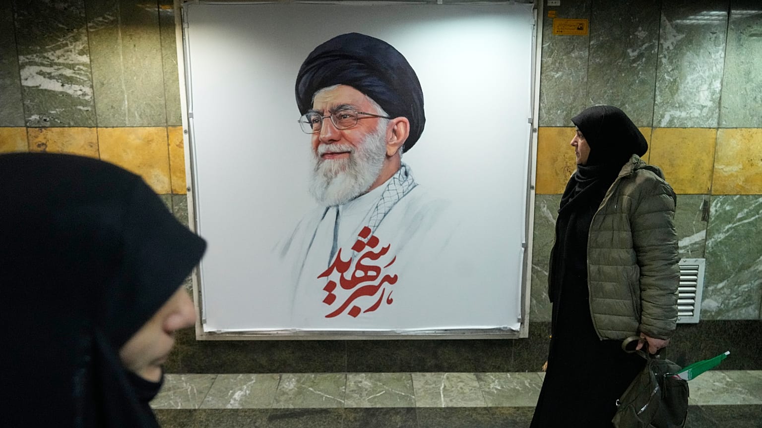 أشخاص يسيرون بجوار صورة المرشد الأعلى الإيراني الراحل آية الله علي خامنئي في ممر محطة مترو الأنفاق في طهران، إيران، الجمعة 13 مارس 2026
