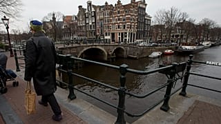 تُظهر هذه الصورة التي التُقطت في 20 مارس 2013 أحد المارة أثناء عبوره جسرًا من جسور أمستردام، هولندا.