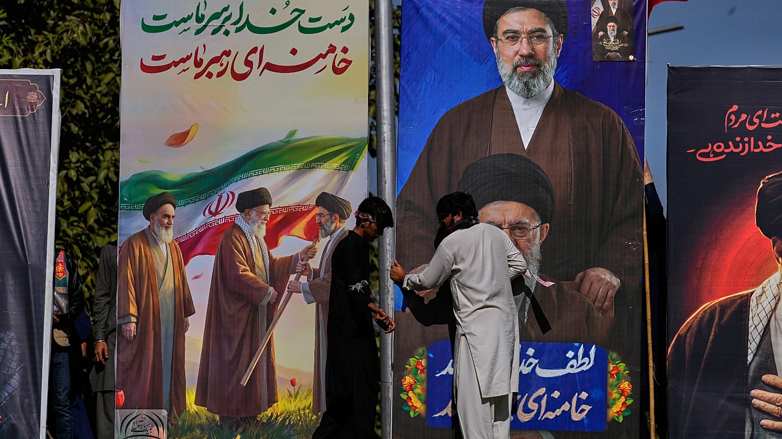 مسلمون شيعة يُعدِّلون لوحات إعلانية ضخمة تُظهر المرشد الأعلى الإيراني آية الله مجتبى خامنئي ووالده الراحل آية الله علي خامنئي خلال التجمع السنوي لـ يوم القدس