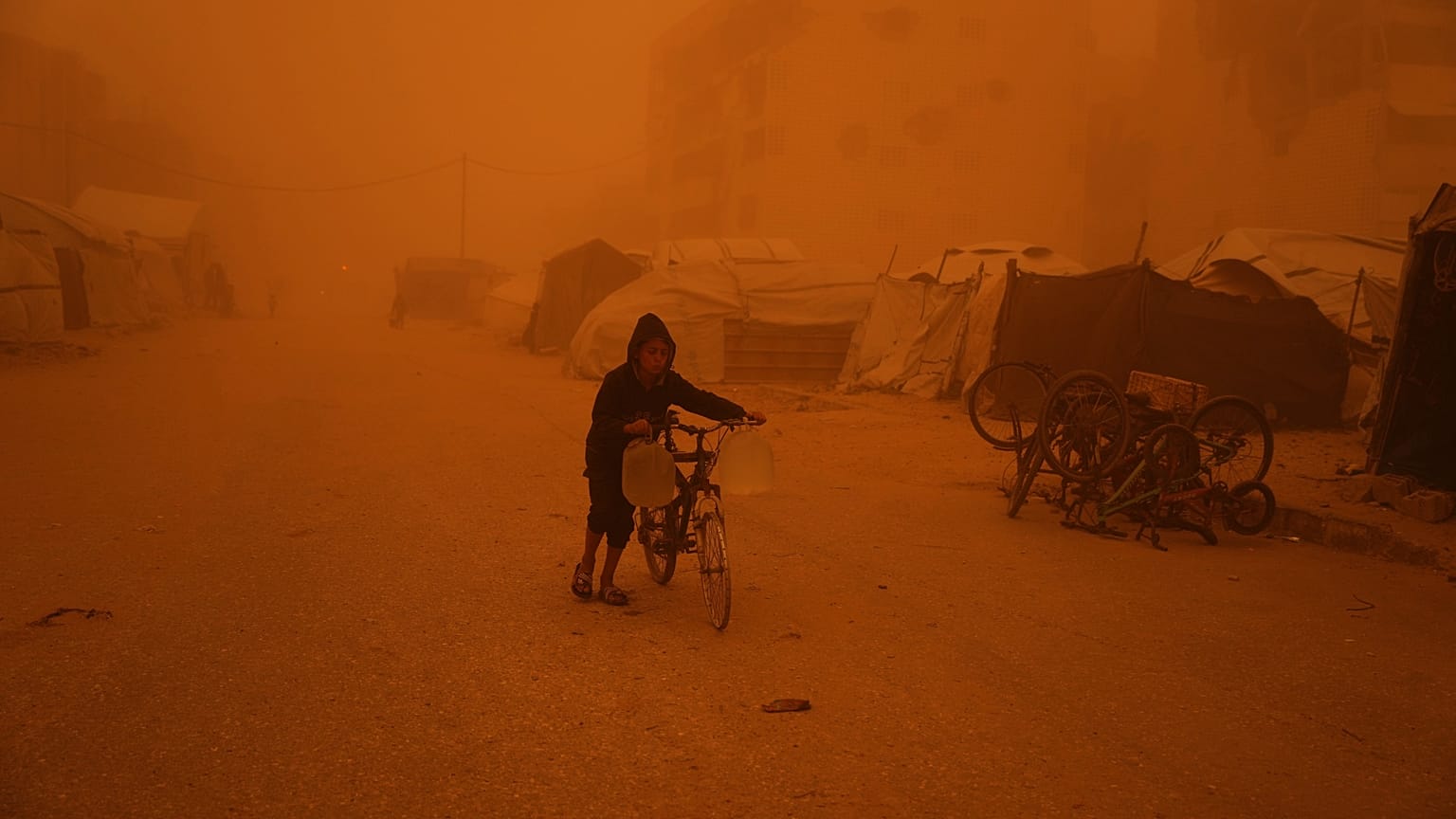 Un niño empuja una bicicleta cargada con bidones de agua en plena tormenta de arena en Jan Yunis, en el sur de la franja de Gaza.