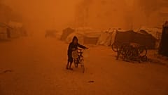 Ein Junge schiebt ein Fahrrad mit Wasserkanistern durch einen Sandsturm in Chan Junis im Süden des Gazastreifens.