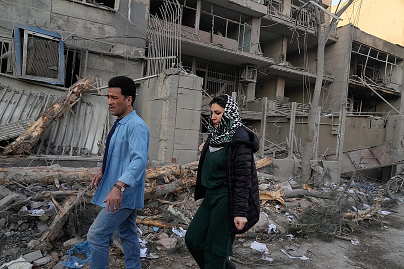 أشخاص يمرّون قرب مبانٍ متضررة بعد ضربة استهدفت مركز شرطة خلال الهجمات العسكرية المشتركة بين الولايات المتحدة وإسرائيل في طهران، إيران، في 2 مارس 2026.