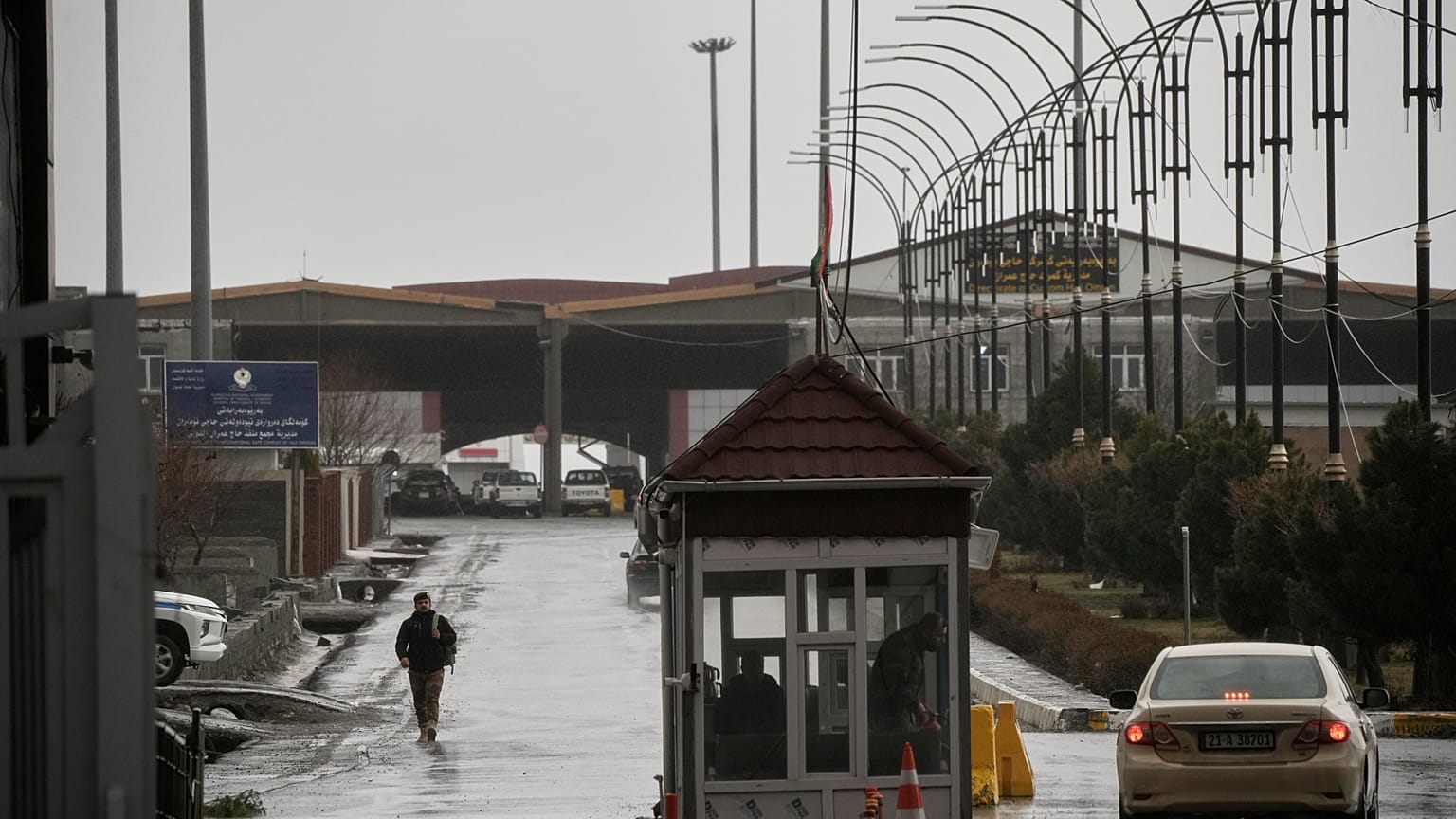 Un agente fronterizo iraquí camina hacia el lado iraquí mientras varios vehículos cruzan el paso fronterizo de Haji Omeran, entre Irán y la Región Autónoma del Kurdistán de Ir