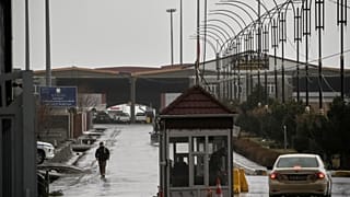 Un agente fronterizo iraquí camina hacia el lado iraquí mientras varios vehículos cruzan el paso fronterizo de Haji Omeran, entre Irán y la Región Autónoma del Kurdistán de Ir