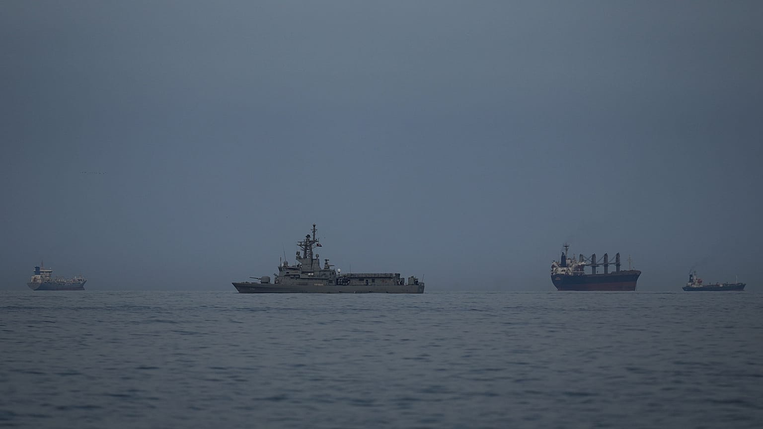 A UAE navy vessel patrols next to cargo ships and oil tankers in the Strait of Hormuz as seen from Khor Fakkan, United Arab Emirates, Wednesday, March 11, 2026