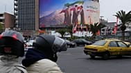 Motorbikes drive past a billboard showing late Ayatollah Ali Khamenei handing the country’s flag to his son and successor Ayatollah Mojtaba Khamenei, in Tehran, 10 March 2026
