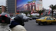 Un cartellone mostra il defunto ayatollah Ali Khamenei mentre consegna la bandiera del Paese al figlio e successore Mojtaba Khamenei, Teheran, 10 marzo 2026
