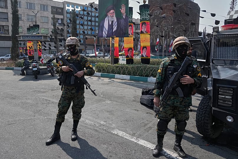Policemen stand guard next to the banners showing portraits of the late Iranian Ayatollah Ali Khamenei at the Enqelab-e-Eslami square in downtown Tehran, 14 March 2026