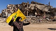  لبنانية تحمل علم حزب الله في قريتها التي دمرتها الحرب الإسرائيلية في كفركلا جنوب لبنان، الثلاثاء 18 فبراير/شباط 2025.