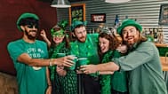 Eine Gruppe Menschen feiert den St.-Patrick's-Day in einem Pub.