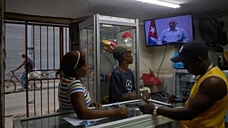 Unas personas dentro de una tienda de conveniencia escuchan al presidente cubano Miguel Díaz-Canel hablando en televisión en La Habana, Cuba, el viernes 13 de marzo de 2026