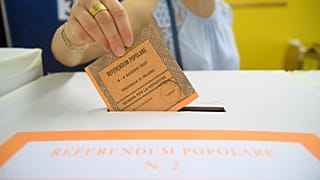 FILE: A woman casts her ballot in a box for referendums on citizenship and job protections, at a polling station in Milan, 8 June 2025