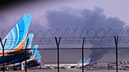 FlyDubai-Flugzeuge, die auf dem internationalen Flughafen von Dubai geparkt sind, während im Hintergrund Rauch aufsteigt, nachdem eine Drohne einen Treibstofftank getroffen hat und der Flugbetrieb eingestellt werden musste, Montag, 16. März 2026