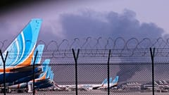 FlyDubai-Flugzeuge, die auf dem internationalen Flughafen von Dubai geparkt sind, während im Hintergrund Rauch aufsteigt, nachdem eine Drohne einen Treibstofftank getroffen hat und der Flugbetrieb eingestellt werden musste, Montag, 16. März 2026