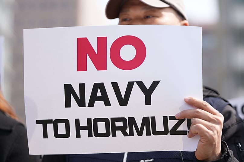 Protester holds a sign against Trump's demands to multiple countries to send warships to keep the Strait of Hormuz open, near US Embassy, South Korea, Monday, March 16, 2026