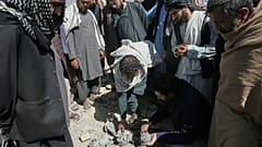 Residenti e poliziotti talebani raccolgono i resti di un proiettile sul luogo di un attacco a Kabul, in Afghanistan, venerdì 13 marzo 2026.