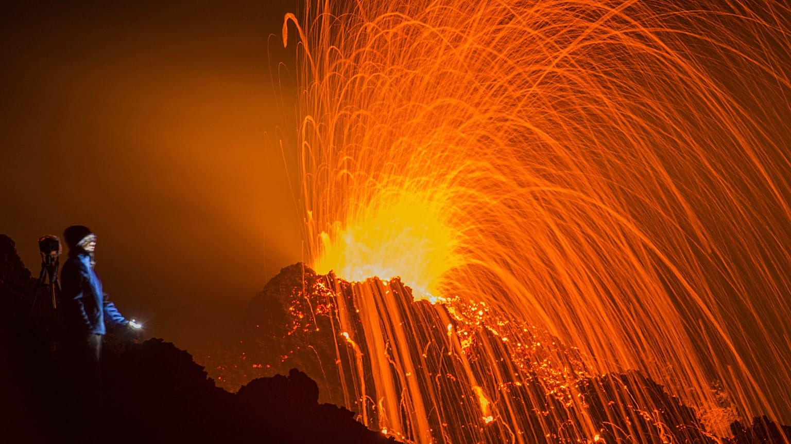 FILE - In this Thursday, Feb. 5, 2015 file photo, a person looks at the Piton de la Fournaise volcano in eruption, in the French Indian Ocean island of La Reunion.