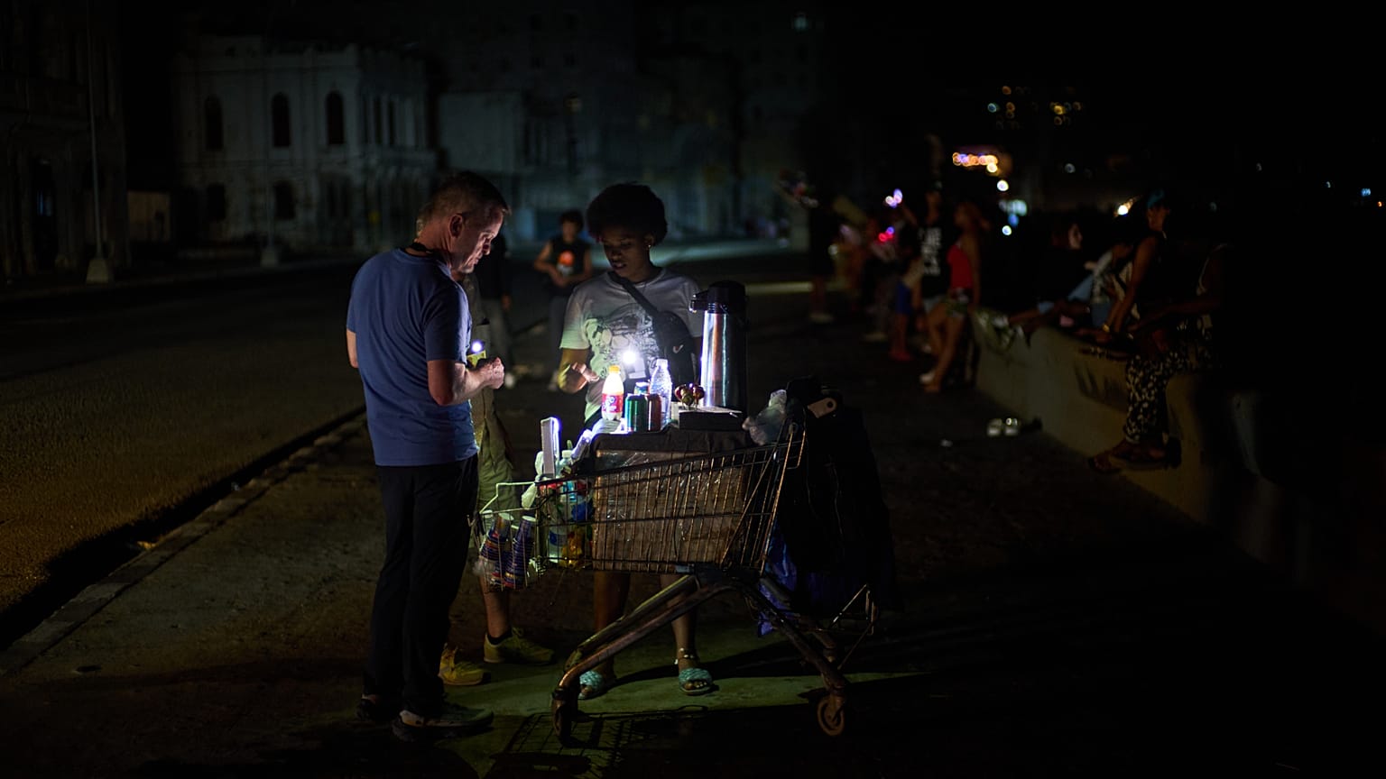 بائع جوال يخدم زبونا على جادة ماليكون خلال انقطاع للتيار الكهربائي في هافانا