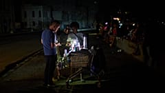 Ein Straßenhändler bedient auf dem Malecón in Havanna einen Kunden bei einem Stromausfall.
