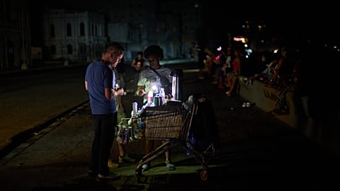 Un vendedor ambulante atiende a un cliente en el Malecón durante un apagón en La Habana