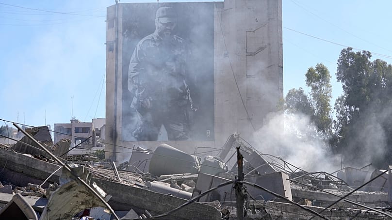 A poster shows the late Hezbollah military commander Imad Mughniyeh, behind a destroyed building that was hit by an Israeli airstrike in Nabatiyeh,March 5, 2026