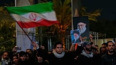 يُلوّح محتجون بالأعلام الإيرانية بينما يرفع آخر صورة للمرشد الأعلى آية الله علي خامنئي، الذي قتل في غارة جوية أمريكية في طهران، خلال جنازة رمزية في بغداد