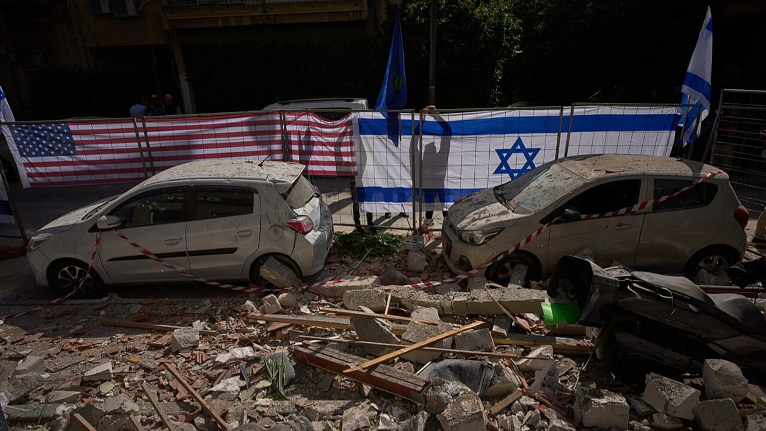 Israeli authorities hang Israeli and U.S. flags at the site struck by an Iranian missile that killed two people, in Ramat Gan, Israel, Wednesday, March 18, 2026.