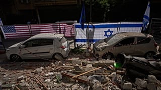 Israeli authorities hang Israeli and U.S. flags at the site struck by an Iranian missile that killed two people, in Ramat Gan, Israel, Wednesday, March 18, 2026.